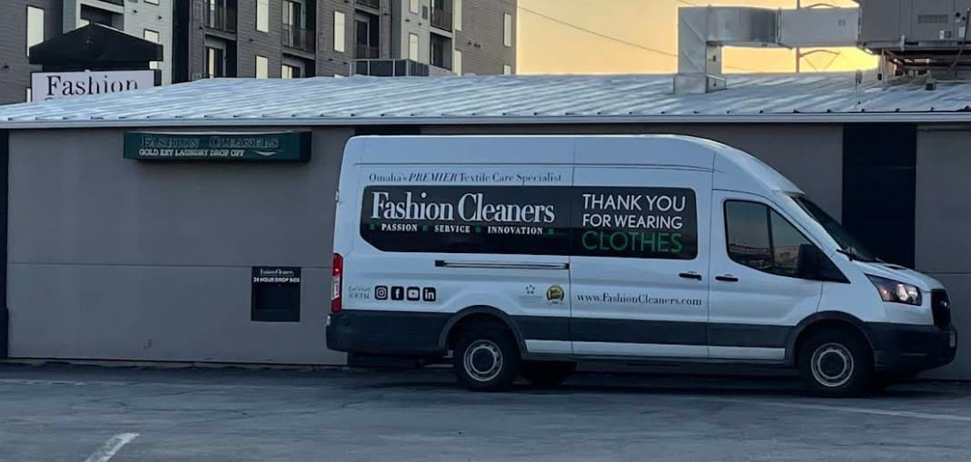 White van parked in front of a building, displaying branding for 