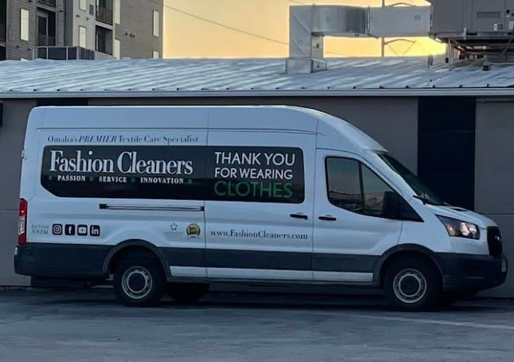 Fashion Cleaners A white Fashion Cleaners delivery van is parked, displaying the message "THANK YOU FOR WEARING CLOTHES" on its side.